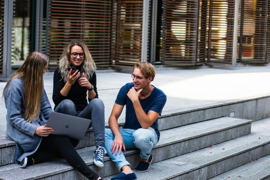 Current image: Three young professionals having a friendly chat while sitting on outdoor steps.